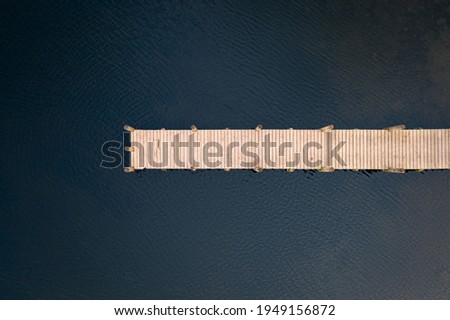Birds eye view of wooden jetty leading out over lake taken with drone. Royalty-Free Stock Photo #1949156872