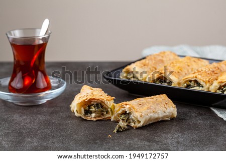 Traditional Turkish spinach pastry rolls ( Ispanakli borek ) served on a porcelain plate. Homemade recipe made using spinach and cheese fillings inside phyllo sheet rolls.  Royalty-Free Stock Photo #1949172757