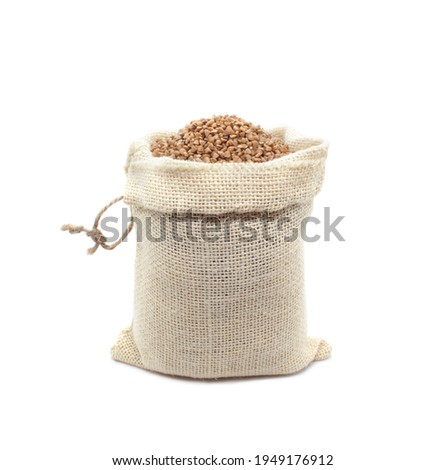 Buckwheat in burlap bag isolated on white background. Raw buckwheat groats in open bag. Close-up. Royalty-Free Stock Photo #1949176912