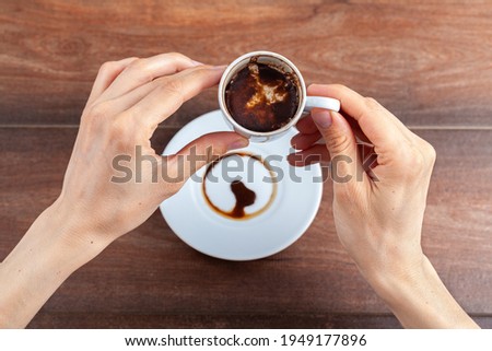 A caucasian woman is performing fortune reading ( kahve fali ) using leftover coffe grounds in ceramic Turkish coffe cup. A popular activity in Turkey. Coffee drops form shapes and patterns. Royalty-Free Stock Photo #1949177896