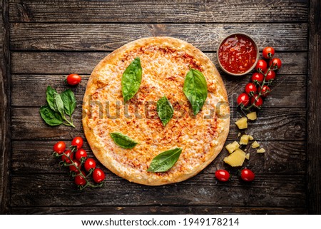 Tasty cheese pizza and cooking ingredients tomatoes and basil on wooden background. Top view