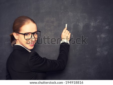 business woman teacher with glasses and a suit with chalk   the lost in thought at a school board