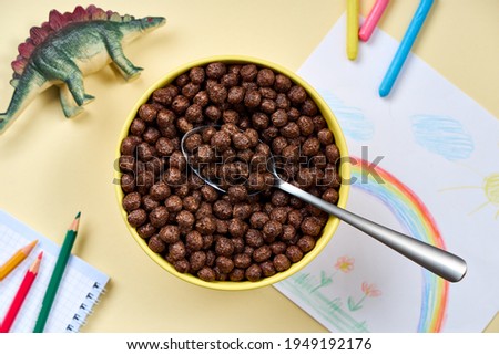 Top View chocolate cornflakes in a bowl on the background of children`s drawing and toys.