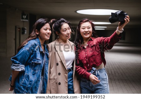 Asian female friends bloggers creating content for social media while making a video with a camera.