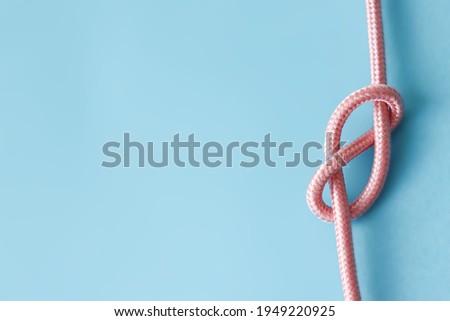 Blue background picture with a pastel pink rope. A concept for tying the knot, marriage and wedding