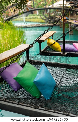 Comfortable colorful pillows lay on rope netting in garden for resting and relaxation.
