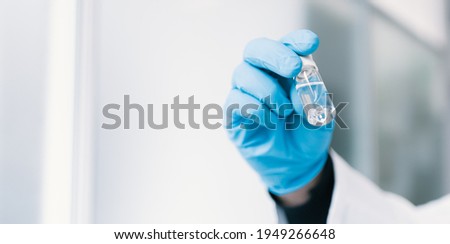 hand with blue gloves holding a glass container with covid-19 vaccine, flu, measles, corona. space for copy space, horizontal picture