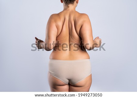 Overweight woman with fat hips and buttocks, obesity female body on gray background, studio shot