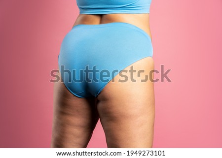 Overweight woman with fat hips and buttocks, obesity female body on pink background, studio shot