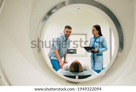 Professional Doctor Radiologist In Medical Laboratory Controls magnetic resonance imaging or computed tomography or PET Scan with Female Patient Undergoing Procedure.