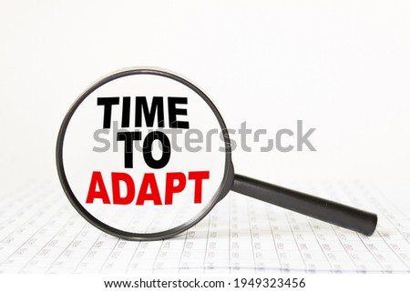 words TIME TO ADAPT IN a magnifying glass on a white background. business concept
