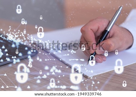 A programmer is taking notes of clients needs to protect cyber security from hacker attacks and save clients confidential data. Padlock Hologram icons over the typing hands. Formal wear