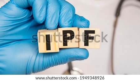 IPF Idiopathic pulmonary fibrosis - word from wooden blocks with letters holding by a doctor's hands in medical protective gloves. Medical concept. Royalty-Free Stock Photo #1949348926