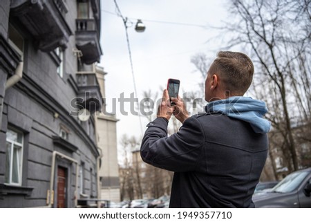 A man takes photos of a building, architecture on his phone