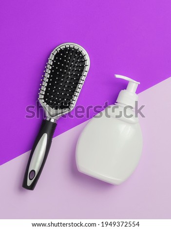 Minimalistic beauty concept. Hair care. Comb and bottle of shampoo on paper background. Top view