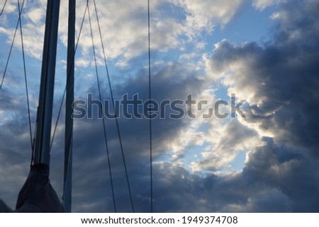 Epic storm cloudscape. White ornamental sunset cumulus clouds. Yacht mast close-up. Soft sunlight. Clear blue sky. Natural pattern, texture, background, graphic resources. Nature, weather