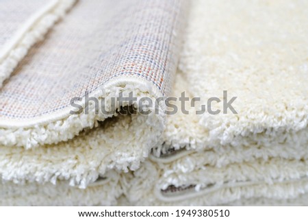 White rugs with a large nap on the counter in the store. Trade in floor coverings made of synthetic materials. Close-up Royalty-Free Stock Photo #1949380510