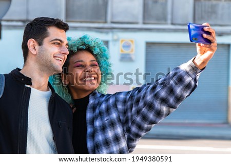 happy multiethnic couple taking a picture with mobile phone on the street
