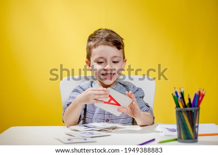 Happy smiling little preschool boy shows letters at home making homework at the morning before the school starts. English learning for kids. Royalty-Free Stock Photo #1949388883