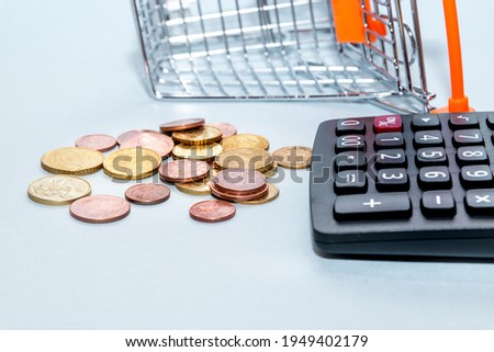 Shopping cart  with scattered coins and a calculator. Concept loan, investment, pension, saving money, financing, collateral, debt, mortgage, financial crisis or rise