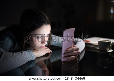 Sad female checking smart phone content in the dark night at home Royalty-Free Stock Photo #1949404468