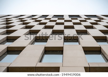 Bottom up view of the facade of a building made of white natural stone with panoramic windows. Modern architecture. Detailed pictures of exterior urban architecture.