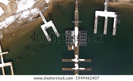 4k aerial drone photo of snowy lake dock in the middle of winter