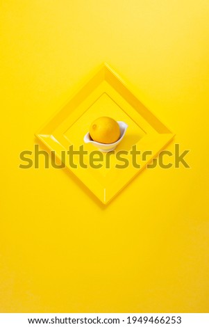 modern yellow photo frame on yellow wall in the shape of a diamond, with a photo of a lemon. Copy space