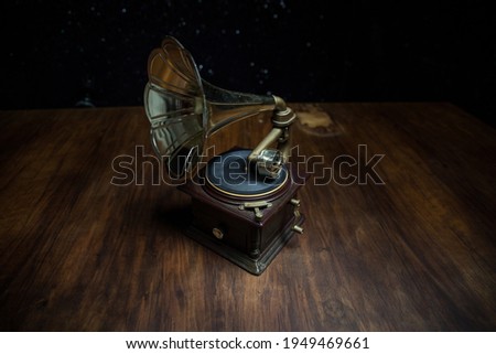 Music concept. Old gramophone on a dark background. Retro gramophone with disc on wooden table with toned backlight. Selective focus