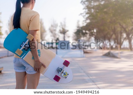 Close up on young women hand hold skateboard, surf skate on public skate ramp park background. Free relax skateboard surf skate trendy concept. Fashion portrait of female hands holding surf skateboard