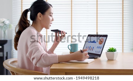 Young happy attractive beautiful asia female talk on mobile phone sit work on desk table at home. Remotely work reskill upskill on distance job or data analysis sale report for business intelligence. Royalty-Free Stock Photo #1949498218
