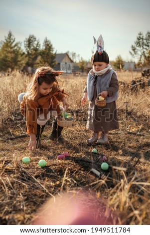 Children in a rabbit costume collect eggs in a basket