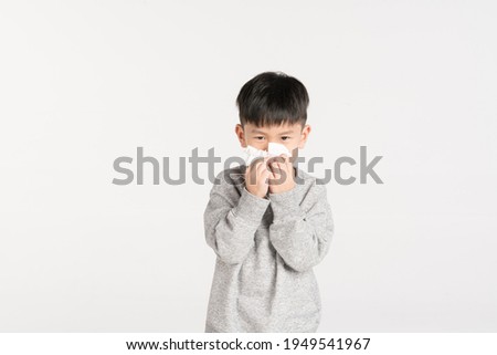 Asian boy about 5 year old holding tissue paper while sneezing or blowing his nose Royalty-Free Stock Photo #1949541967