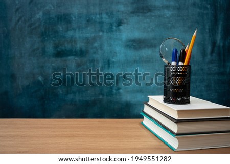 Books on the desk and a blank blackboard. Education concept.