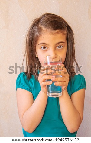 the child holds a glass of water in her hands. selective focus.nature