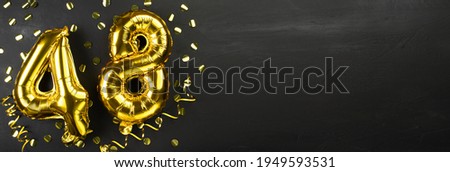 golden foil balloon number forty eight. Birthday or anniversary card with the inscription 48. Black concrete background. Anniversary celebration. Banner. copy space