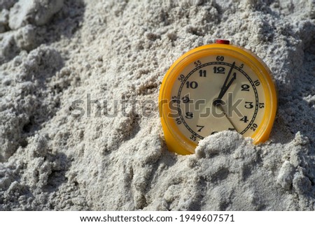 Old mechanical yellow alarm clock with Arabic numerals on the sand