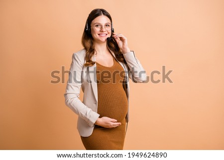 Portrait of pretty cheerful pregnant girl talking on hot line consulting client isolated over beige pastel color background