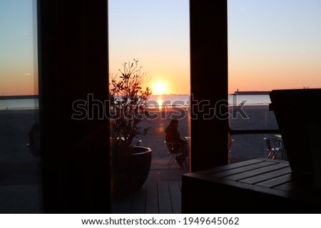 View from the coastal cafe to the ocean at sunset.
On the street we see the silhouette of a man sitting at a table. Conceptual photography on the subject of covid restrictions.