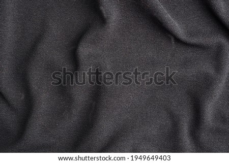 Background is made of black textile material, the texture of a piece of clothing