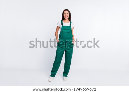 Photo of charming cool lady hands pockets look camera wear green overall isolated white color background