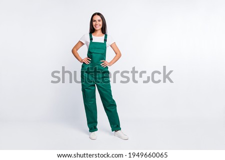 Photo of pretty positive lady hands hips look camera wear green overall isolated white color background Royalty-Free Stock Photo #1949660065