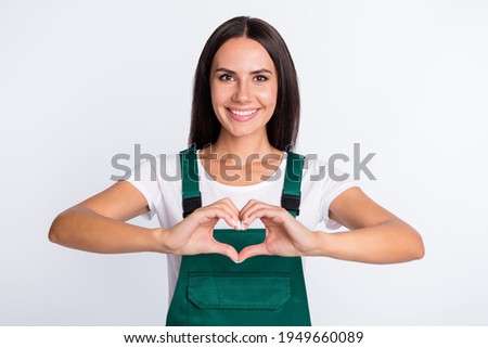Photo of romantic cheerful lady fingers show heart symbol wear green overall isolated white color background