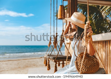 Travel summer vacation concept, Happy traveler asian woman with hat and dress relax on swing in beach cafe, Koh Chang, Thailand Royalty-Free Stock Photo #1949664940