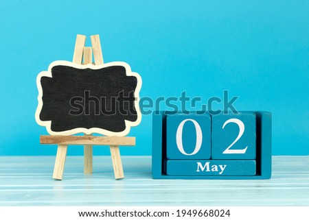 wooden calendar with date 2 May and easel on blue background, place for text, World Scrapbooking Day; World tuna day