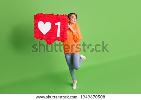 Full length photo of funny amazed young woman hold large like icon shocked isolated on green color background