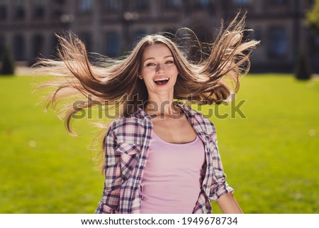 Photo of positive cheerful young woman fly hair good mood university student outside in campus outdoors