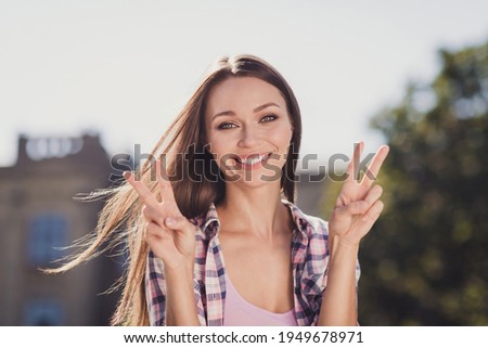 Photo of happy brunette haired woman make v-signs greeting university student outside in park outdoors