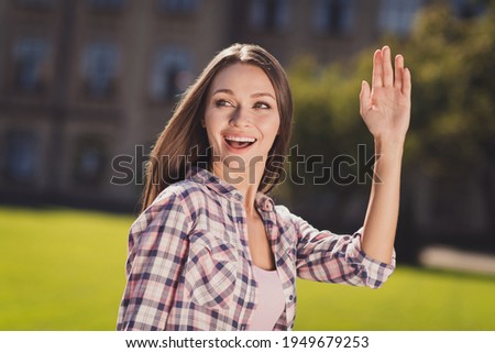 Photo of young cheerful girl student happy positive smile look empty space wave hand hello outside park