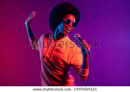 Photo of cheerful singer lady hold mic open mouth wear hoodie eyeglasses isolated gradient neon background Royalty-Free Stock Photo #1949684161